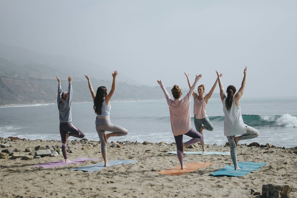 Mehrere Personen, die Yoga am Strand machen